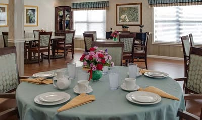 Dining room set up for a meal with flowers and dishes