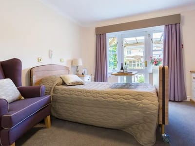 Cozy resident room with a bed and a purple accent chair