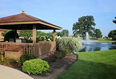 A gazebo by a pond with landscaped gardens