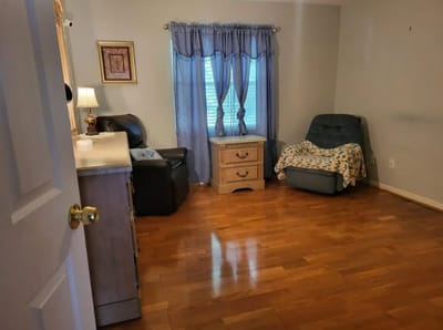 A cozy resident room with wooden flooring and a blue chair