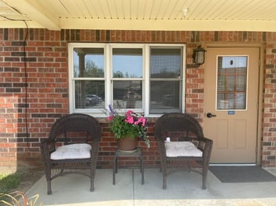 Front entrance of a senior living facility with chairs and flowers