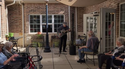 Musician performing for residents on an outdoor patio