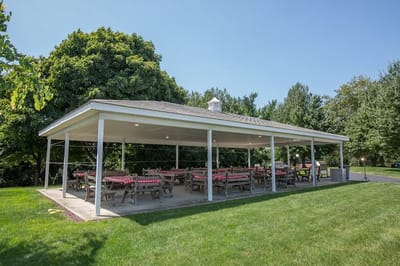 Outdoor pavilion with picnic tables in a landscaped area
