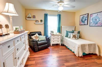 A cozy resident room with a bed and chair