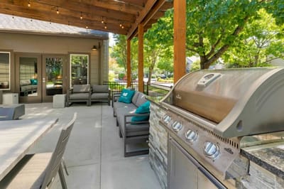 Outdoor seating area with a grill and lush greenery
