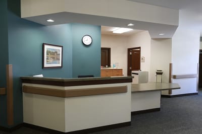 Interior view of a reception area with a clock and artwork