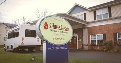 Outdoor view of Gluco Lodge sign with building and transport vehicle