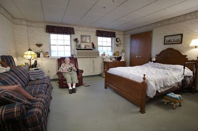 A cozy resident room with an elderly person sitting comfortably