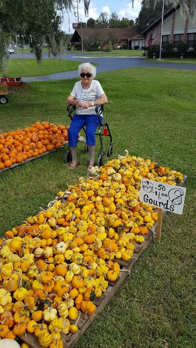 An elderly woman enjoying a gourd market outdoors
