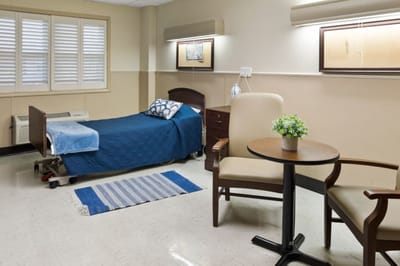 A furnished private resident room with a bed and chair