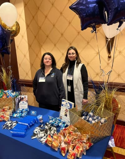 Two staff members at a decorated table with snacks