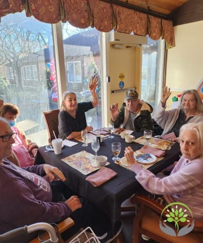 Residents enjoying a meal and waving at the camera