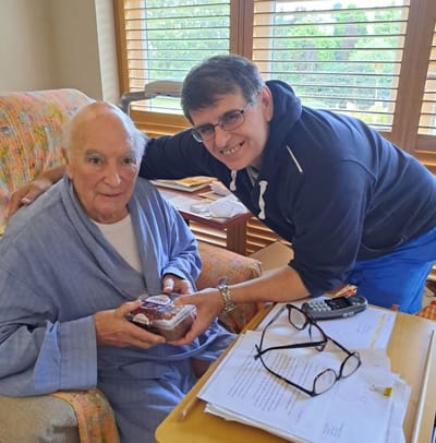 A resident holding a dessert with staff member