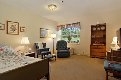 Cozy resident room with bed, chairs, and window view