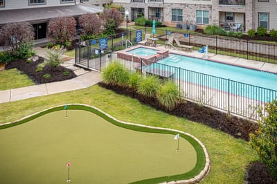 Outdoor pool area with putting green and seating