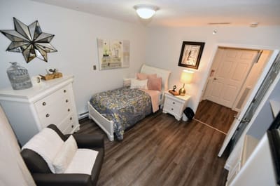 A cozy resident room with a bed and comfortable chair