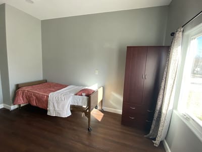A private resident room with a bed and dresser