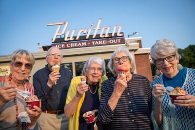 Seniors enjoying ice cream outside with a shop in the background