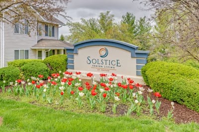 Welcoming entrance sign with flowers at Solstice Senior Living