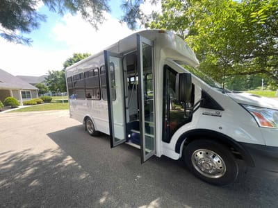 Facility shuttle bus parked outside with open doors