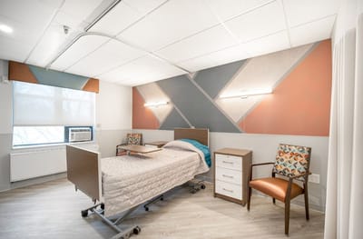 Interior view of a resident's room with a bed and chair