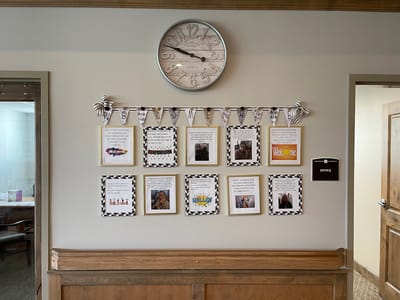 A wall display with framed photos and quotes in a common area