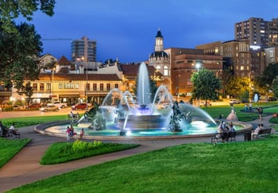 A public fountain in a park with people enjoying the space