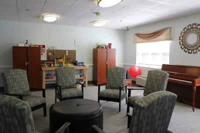A cozy activity room with seating and a piano