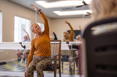 Residents participating in seated exercise class indoors