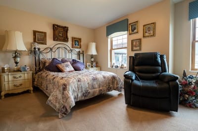 Cozy private bedroom with a floral bedspread and armchair