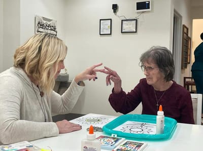A staff member engaging in a craft activity with a resident