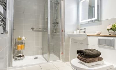 A modern bathroom with a shower and neatly arranged towels