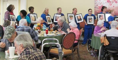 Residents enjoying a meal with staff presenting artwork