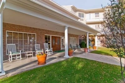 Exterior view of a senior living facility with rocking chairs