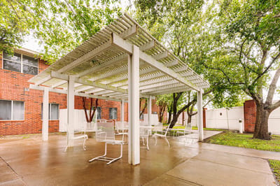 Covered outdoor seating area surrounded by trees