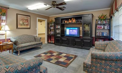 Common area with seating and a television in Wheatland Nursing Center