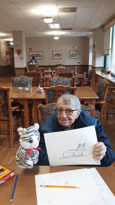 Resident with a puppet and drawing in a common area