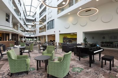 Interior view of a common area with green chairs and a piano