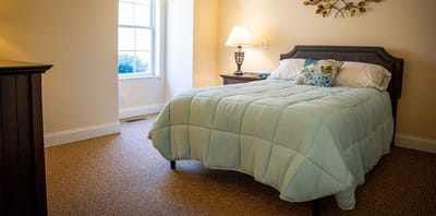 A well-furnished private resident room with a cozy bed