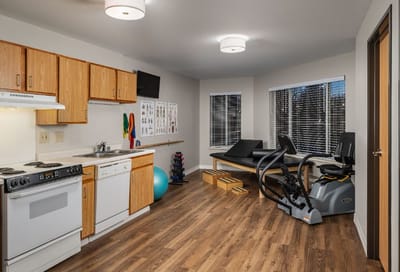 Bright fitness room with exercise equipment and kitchen area