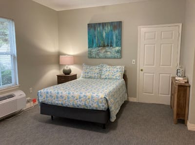 Brightly decorated resident room with a bed and artwork