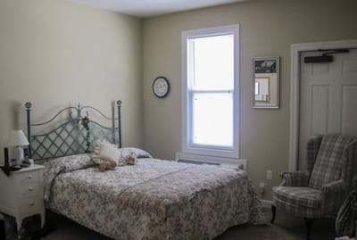 Cozy resident room with floral bedding and a chair