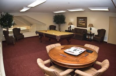 Common area of a senior living facility with seating and a pool table