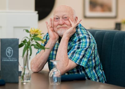 Resident smiling and posing at the dining table