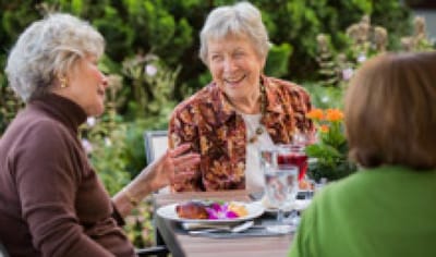 Residents enjoying a meal outdoors in a garden setting