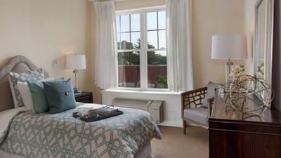 A welcoming private resident room with a bed and chair