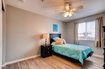 Brightly lit private resident room with a bed and dresser