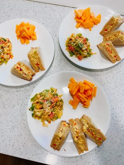 Three plates of food including sandwiches and fruit