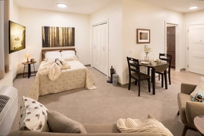 A well-furnished private resident room with a bed and dining area
