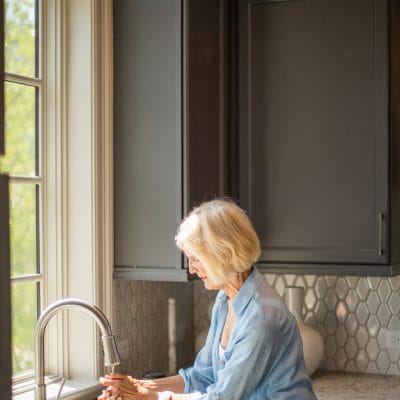 A senior woman washing hands at a kitchen sink